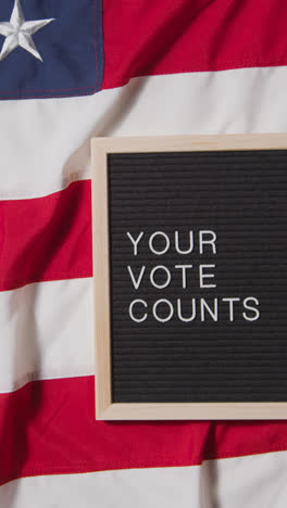 Vertical-Video-Of-Sign-Reading-Your-Vote-Counts-Lying-On-US-Stars-And-Stripes-Flag-For-American-Election-2024-2